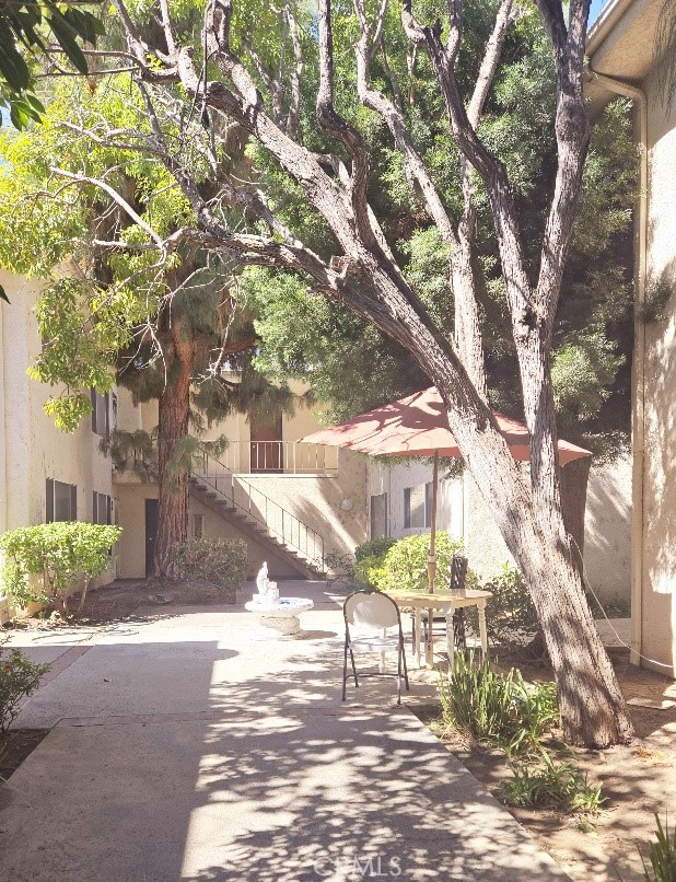 a view of a patio with table and chairs and a large tree