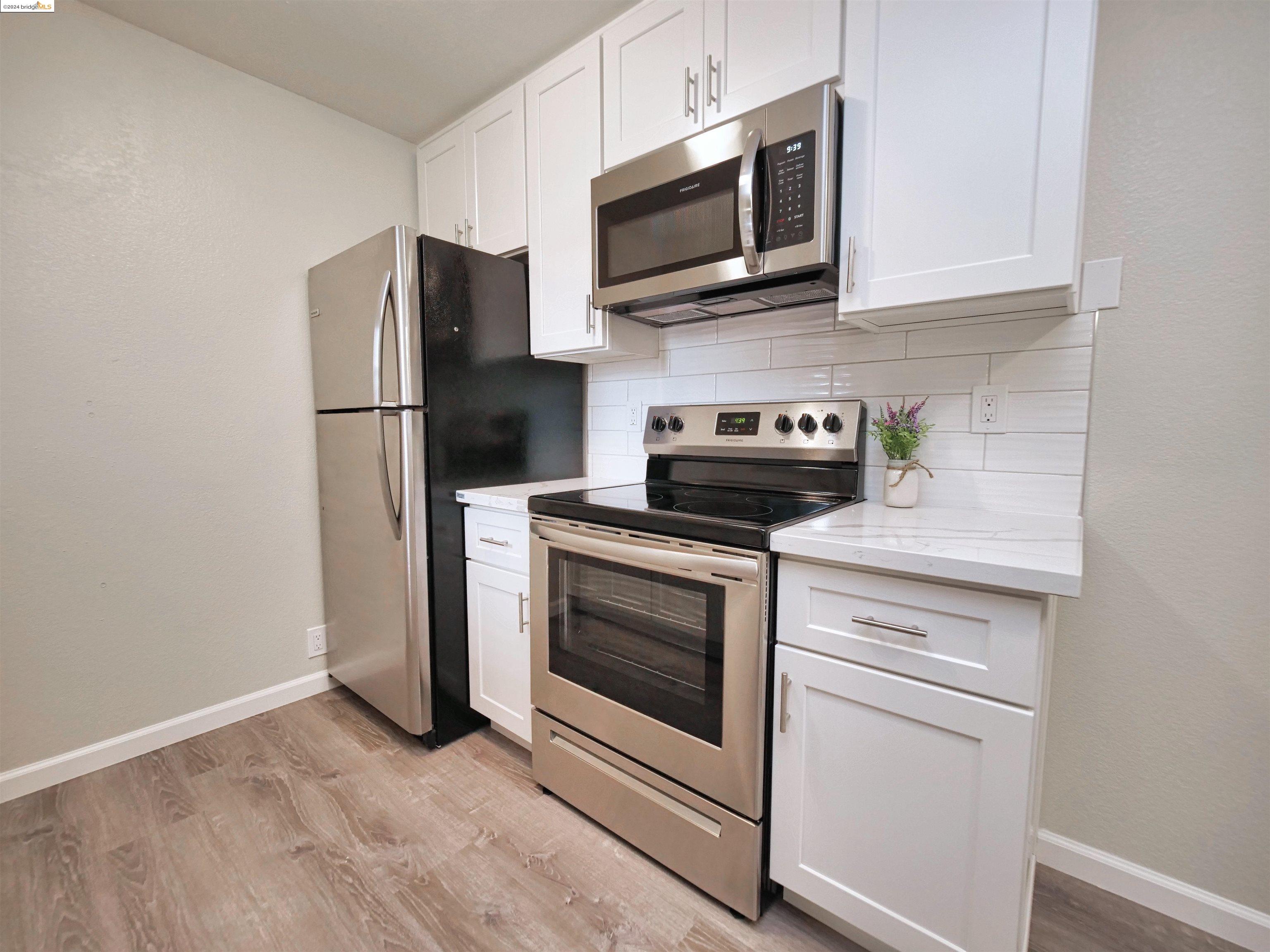 a kitchen with stainless steel appliances white cabinets a stove a microwave and a refrigerator