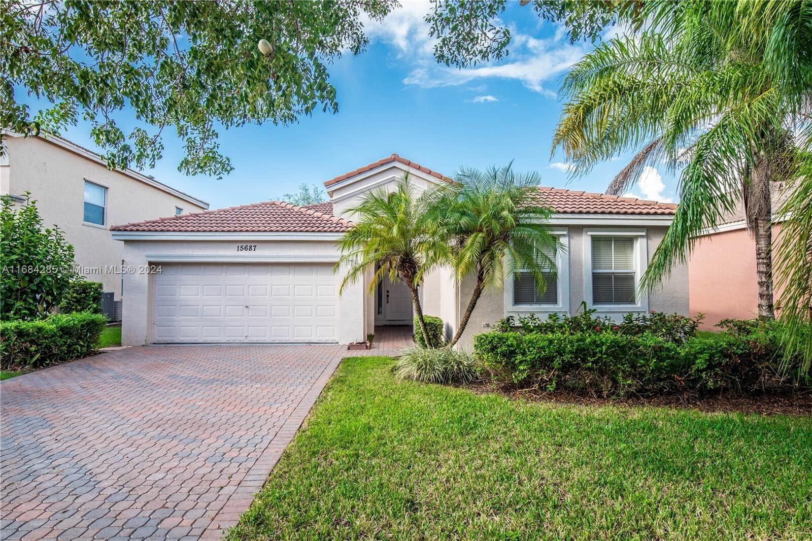 a front view of a house with a garden and palm trees