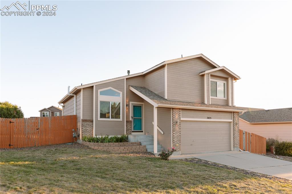 View of front of property with a garage and a front lawn