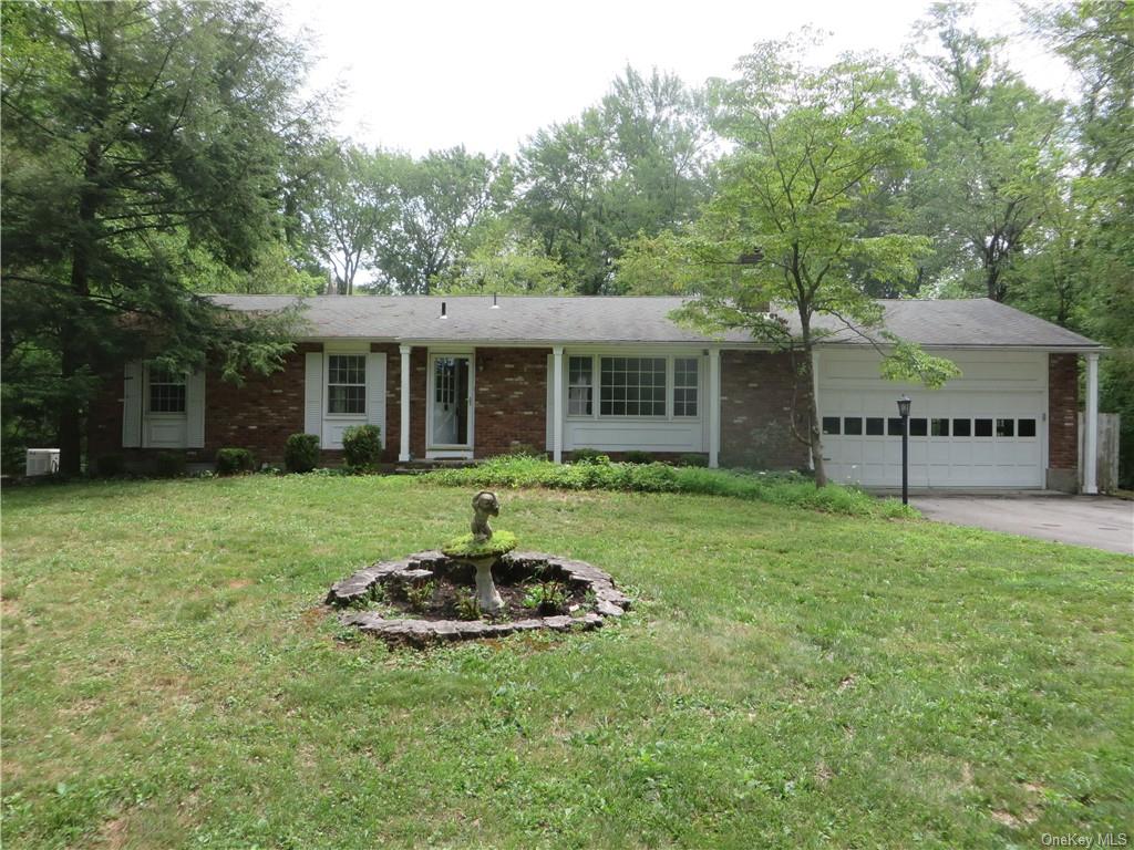 Ranch-style home featuring a garage and a front lawn