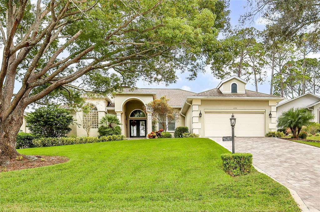 a front view of a house with garden and trees