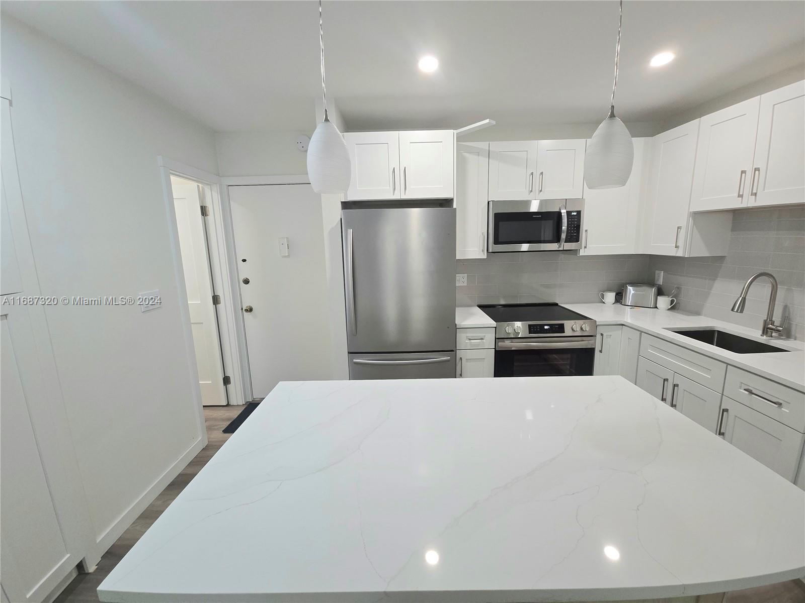 a kitchen with stainless steel appliances a refrigerator sink and white cabinets