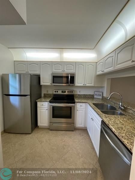 a kitchen with granite countertop a refrigerator stove and microwave