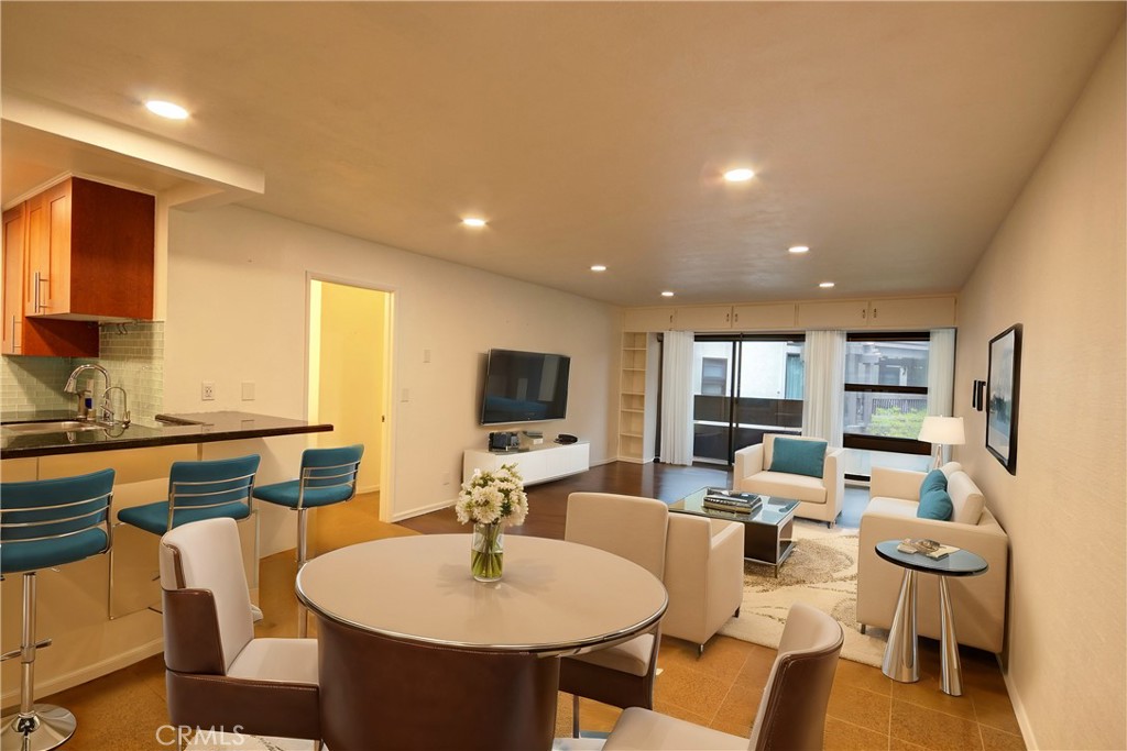 a living room with furniture a flat screen tv and kitchen view