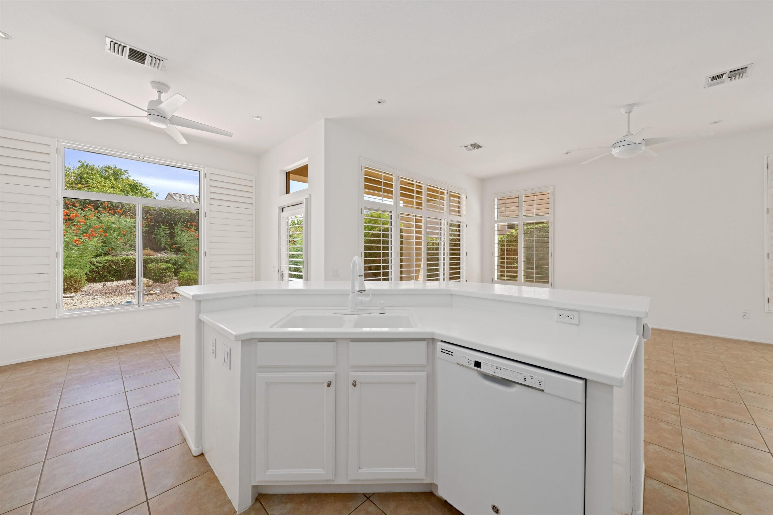 a kitchen with white cabinets and window