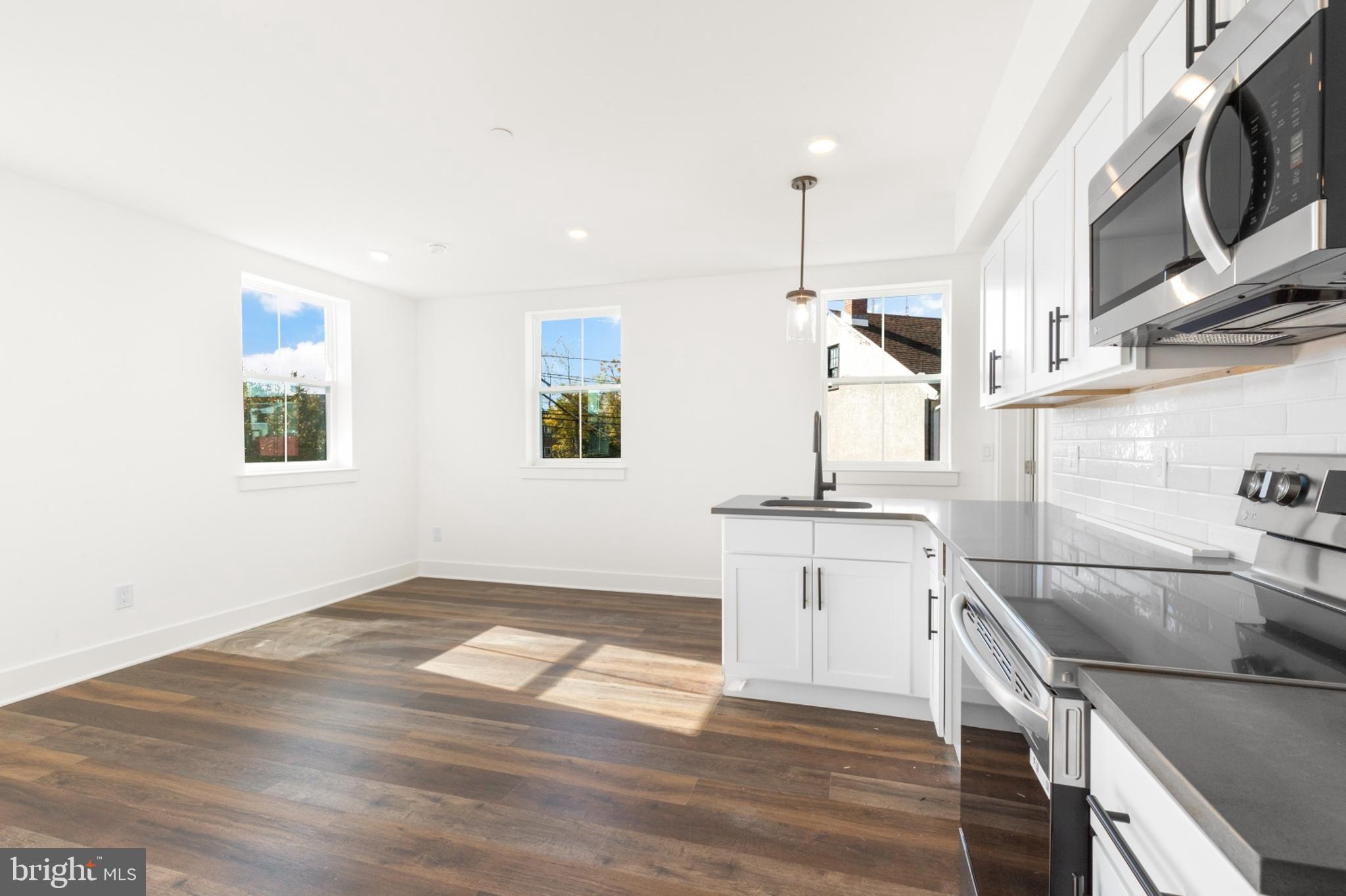 a kitchen with a sink dishwasher a stove and a microwave oven with wooden floor