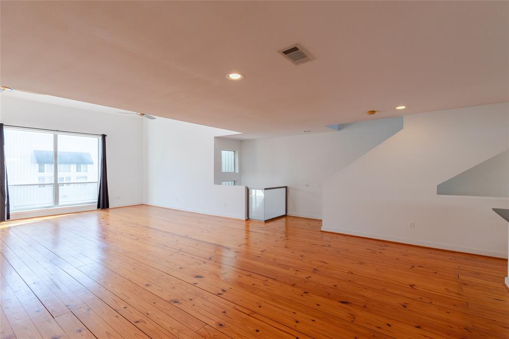 a view of an empty room with wooden floor and windows