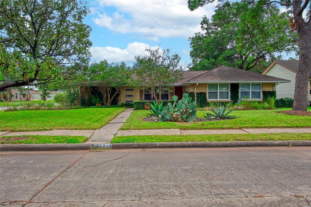 a view of a house with a big yard plants and large trees