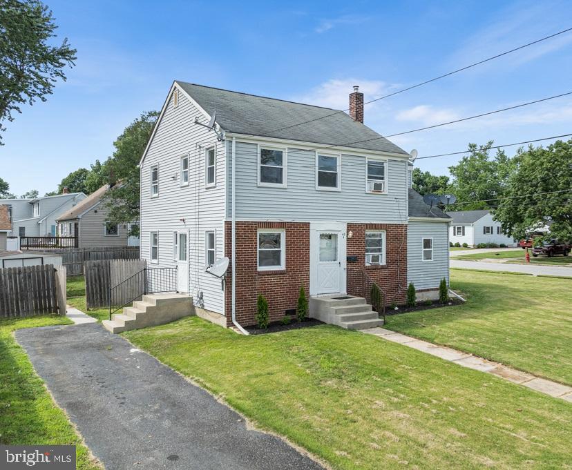 a front view of house with yard and trees in the background