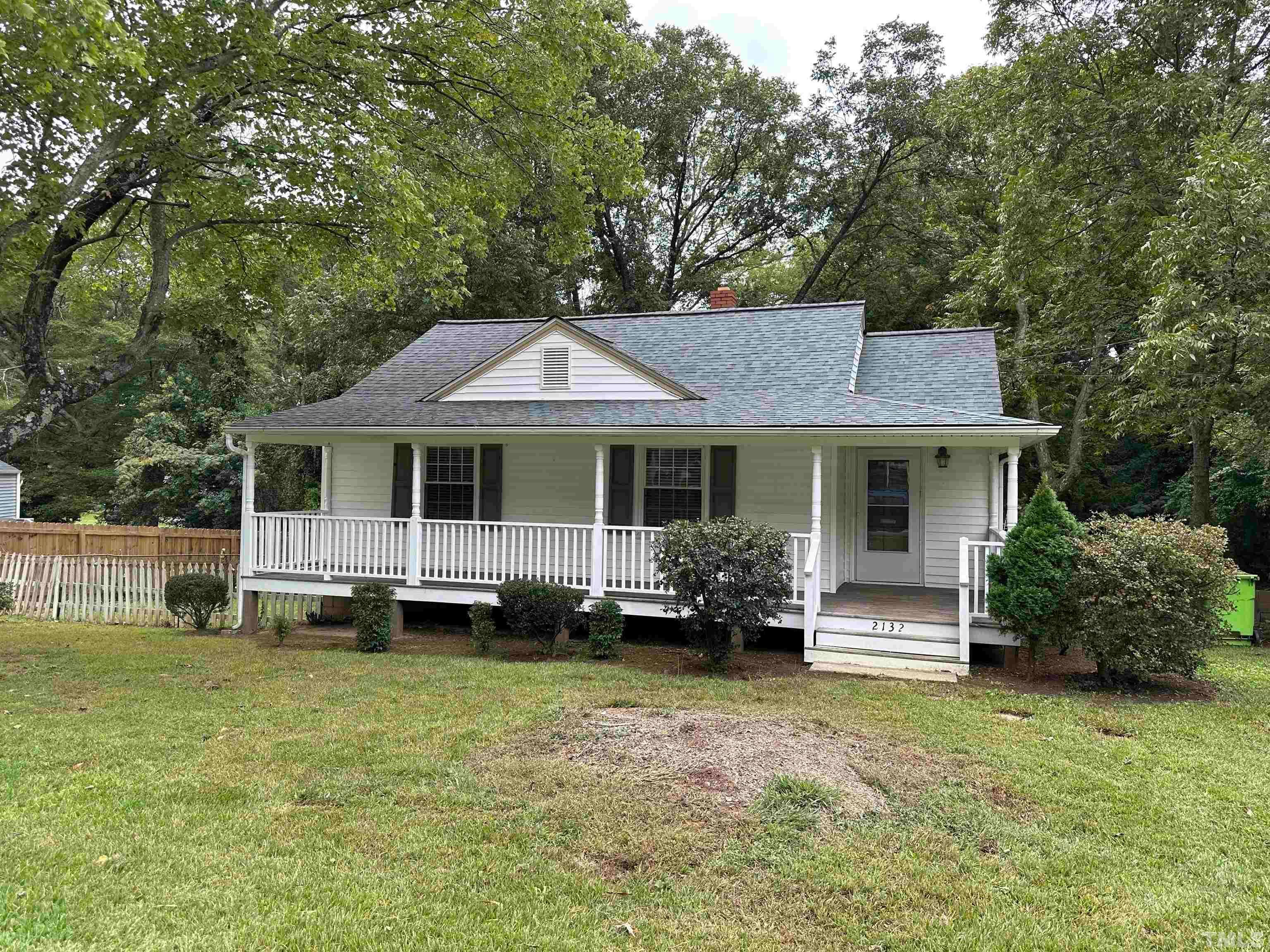 a front view of a house with a garden and trees