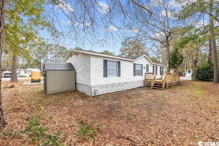 Rear view of property featuring a storage shed and