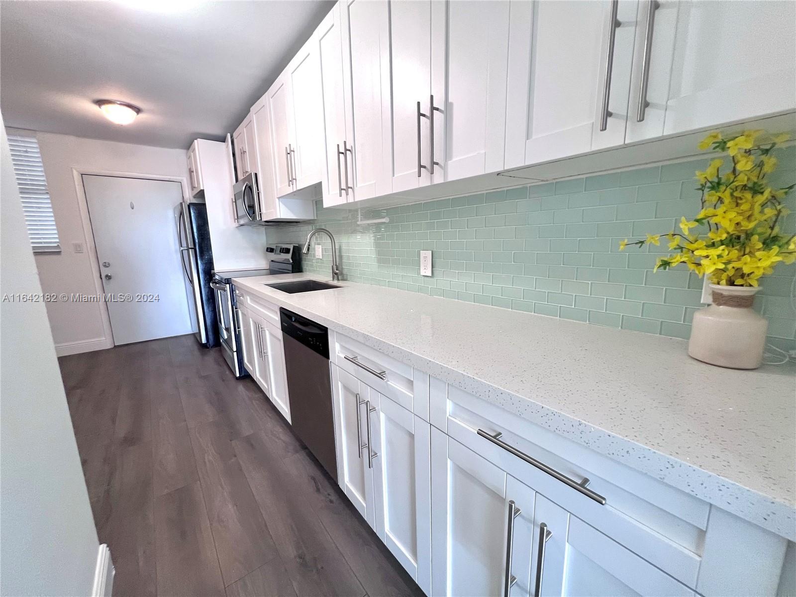 a kitchen with stainless steel appliances a white cabinets wooden floors and a white top