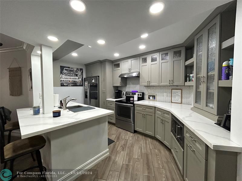 a kitchen with a sink a counter top space stainless steel appliances and cabinets