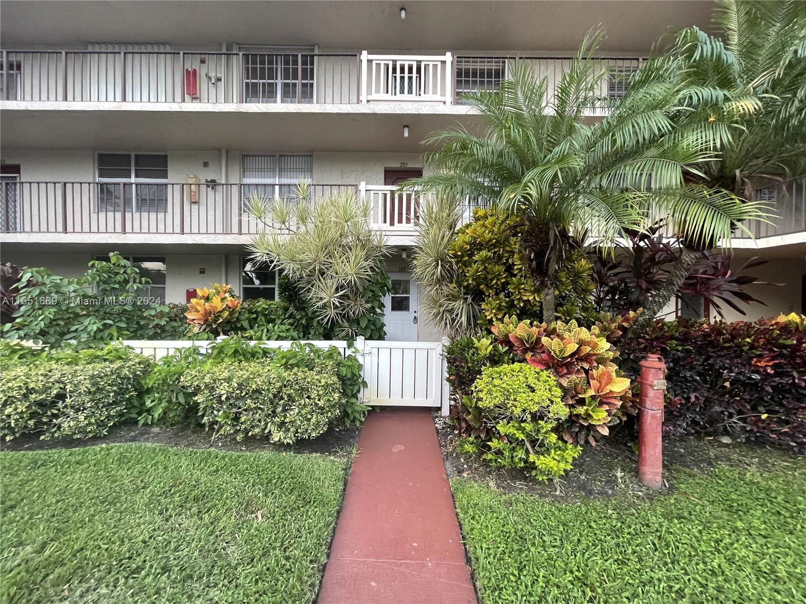 a front view of a house with a yard and potted plants