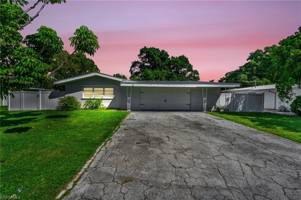 Ranch-style home with a garage and a yard