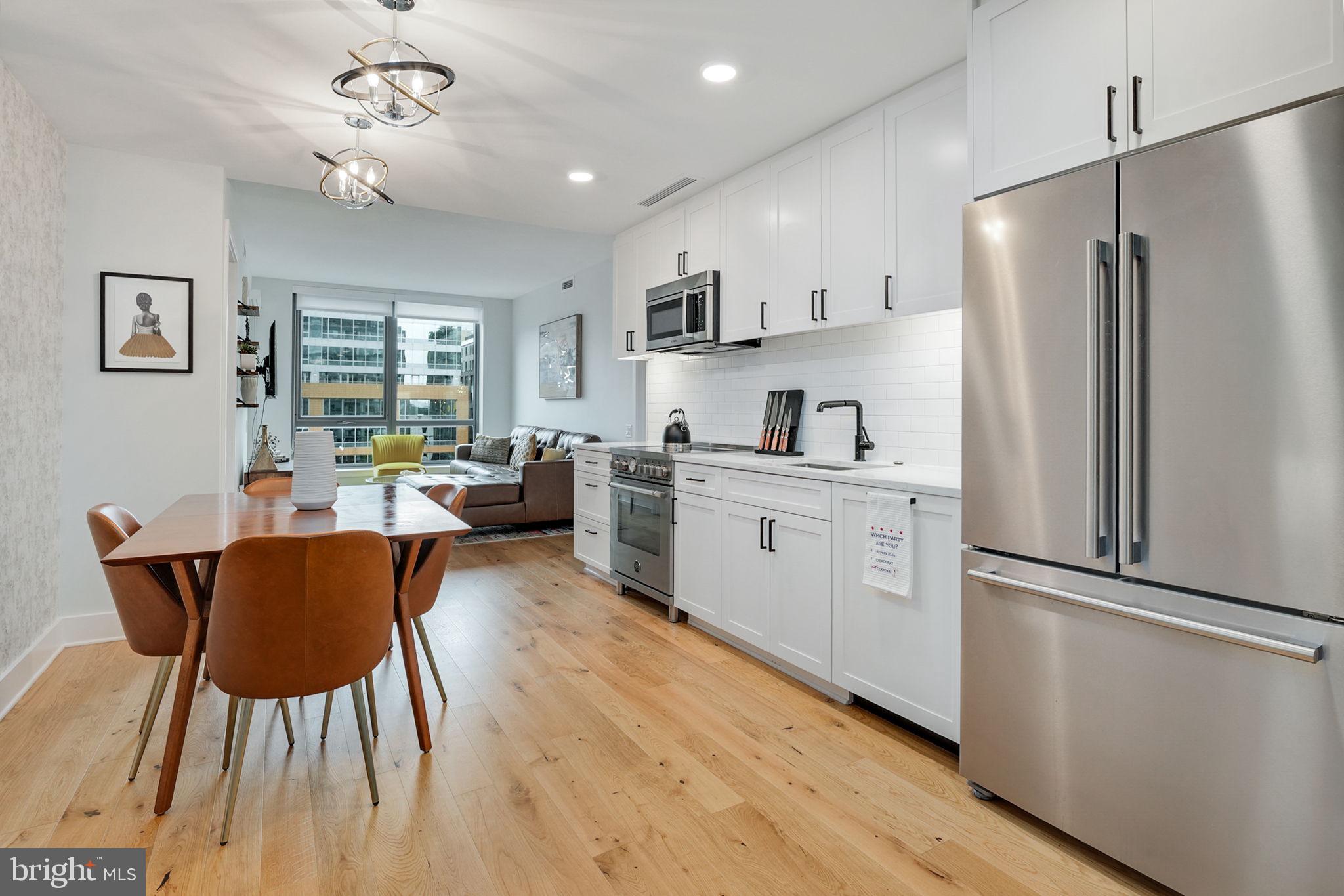 a kitchen with stainless steel appliances a dining table chairs refrigerator and sink