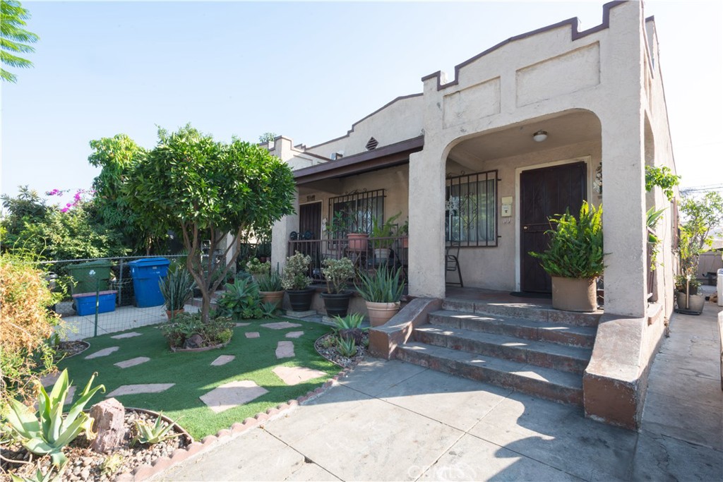 a view of a house with brick walls plants and large tree