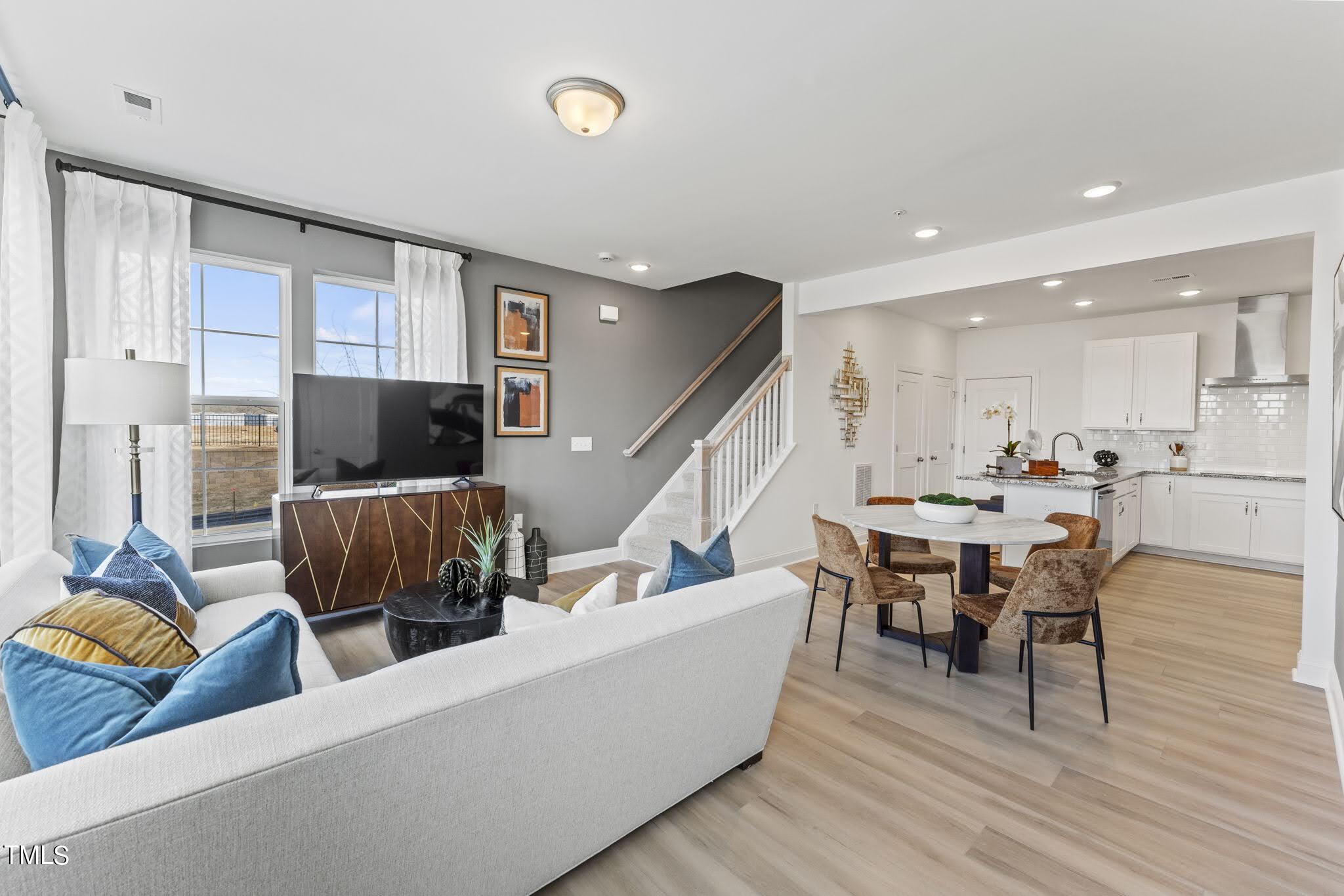 a living room with furniture kitchen view and a wooden floor