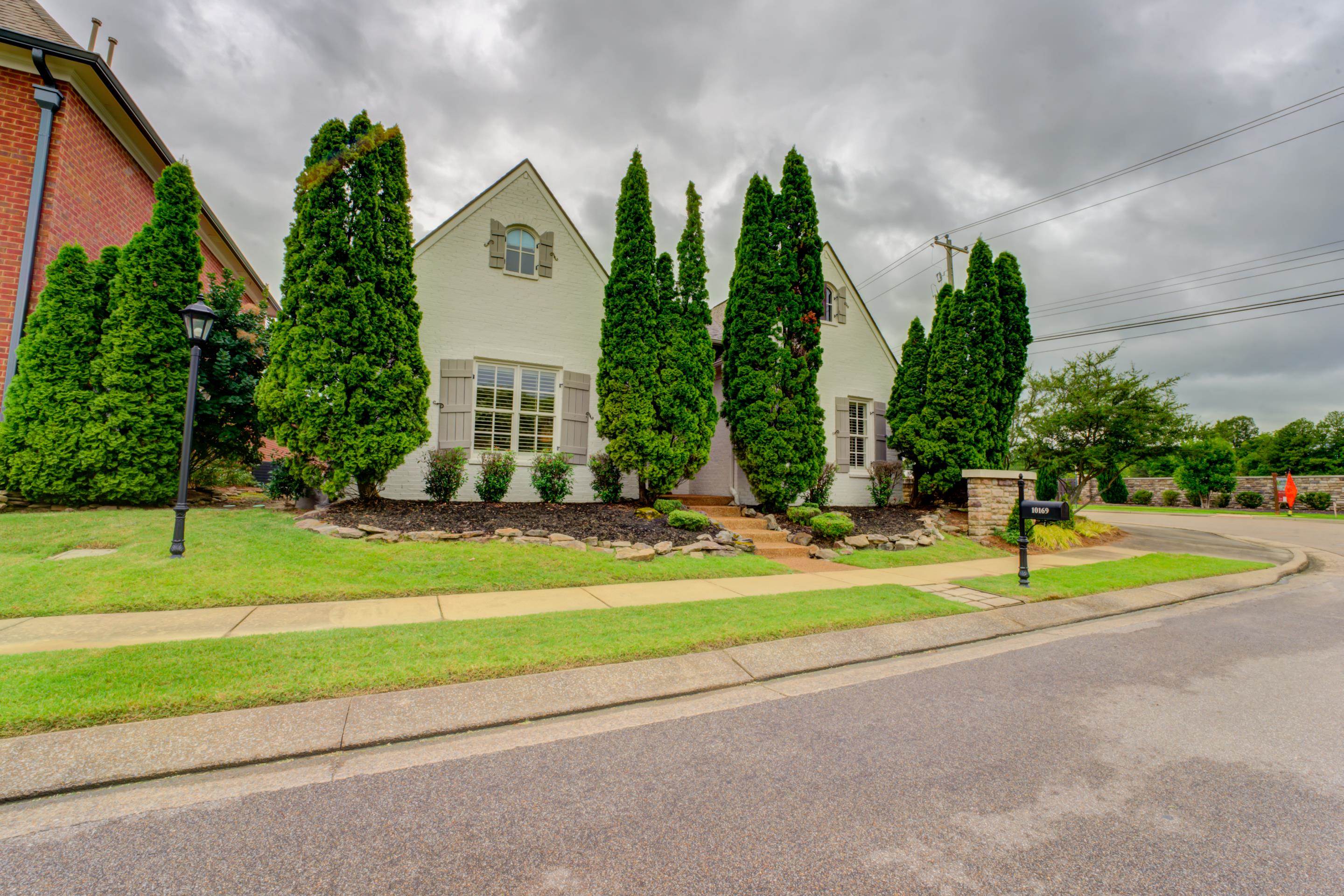 a front view of a house with garden and trees