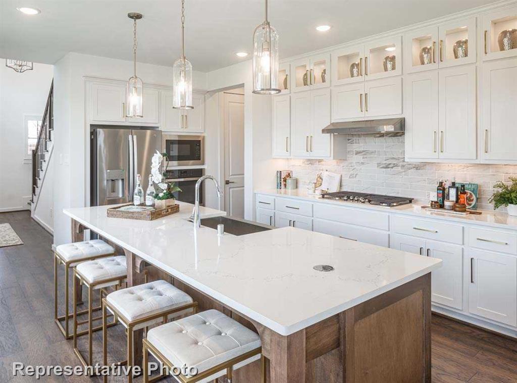 a kitchen with a white center island a counter space and stainless steel appliances