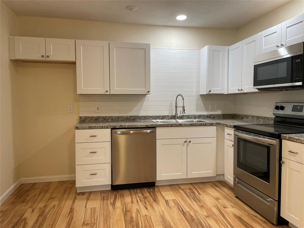 a kitchen with granite countertop a sink cabinets and stainless steel appliances