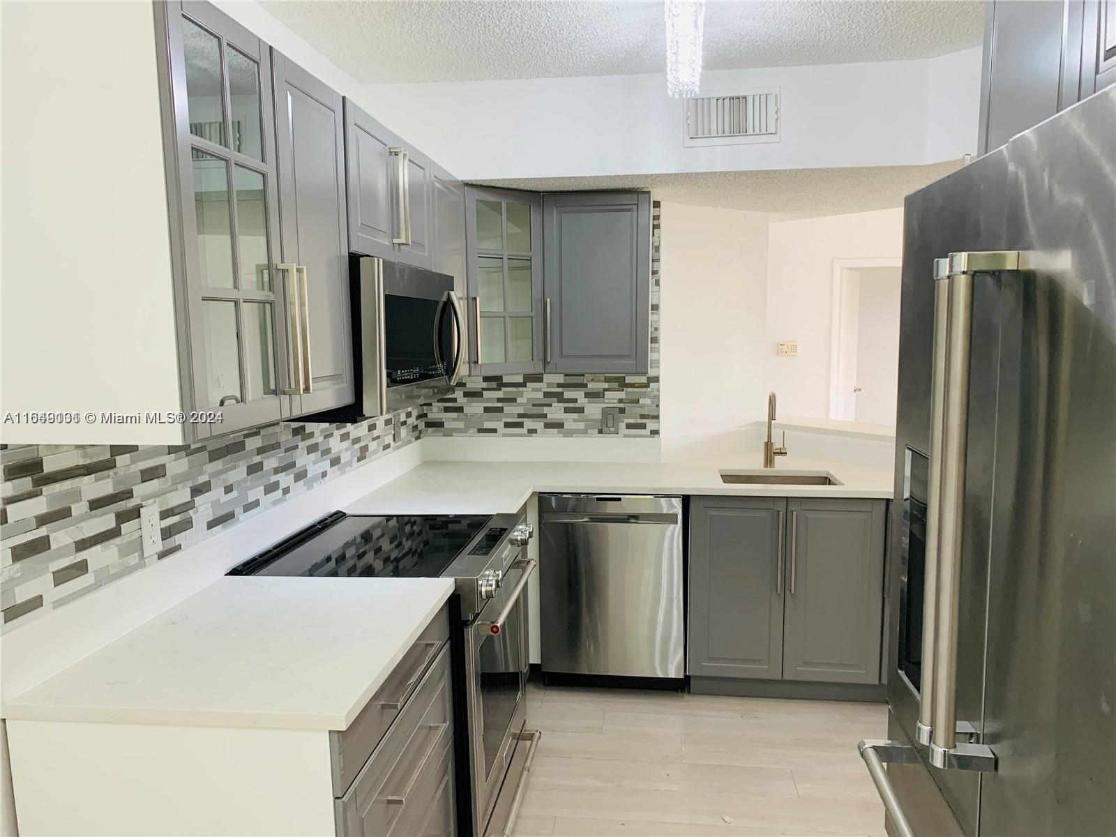 a kitchen with stainless steel appliances a sink and a refrigerator