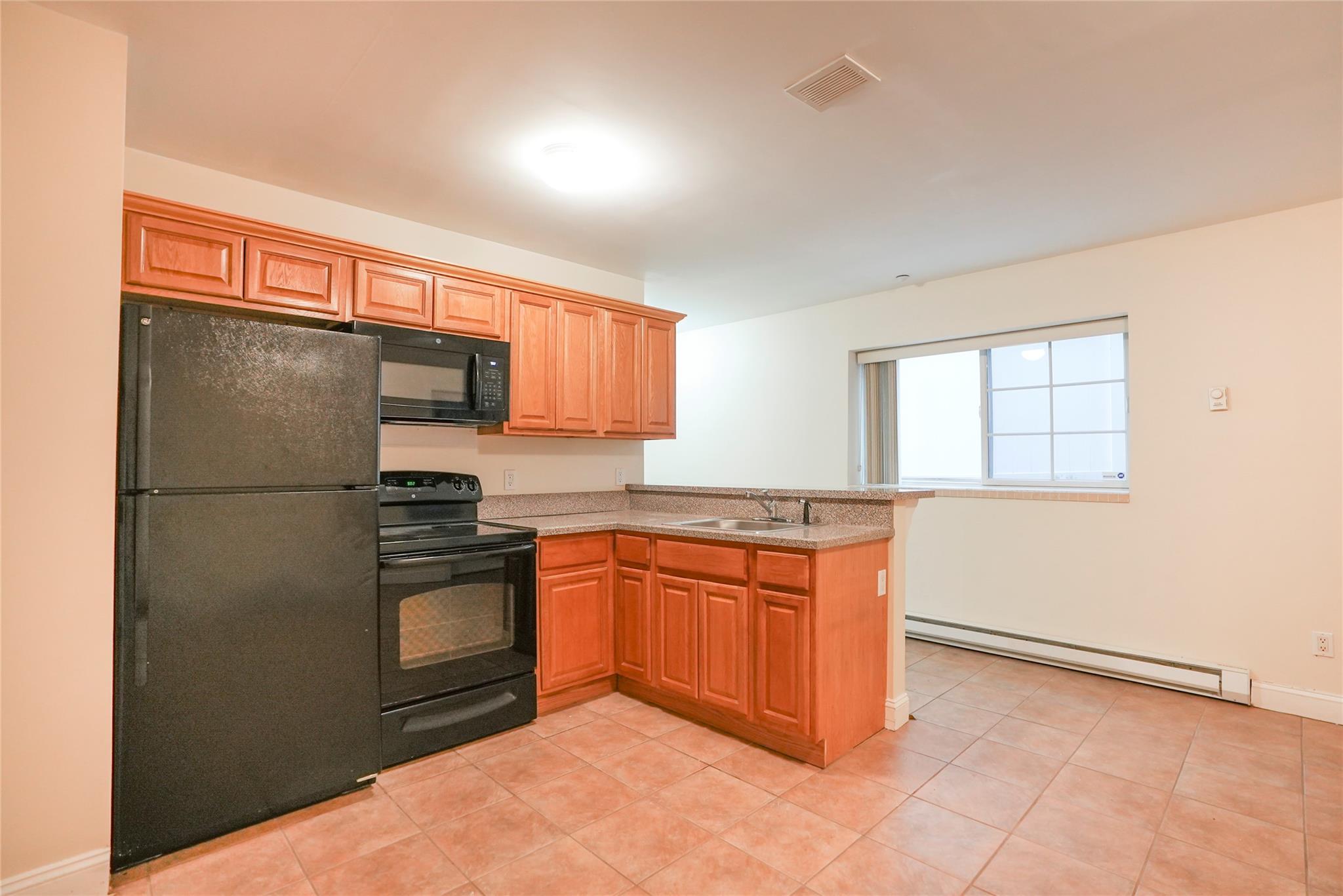 Kitchen featuring kitchen peninsula, sink, a baseboard radiator, and black appliances