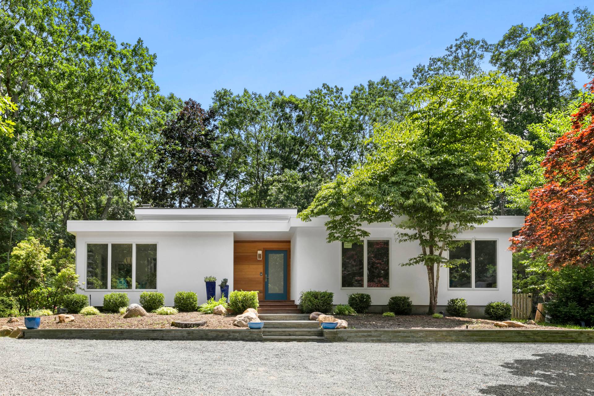 a front view of a house with a lots of trees and plants