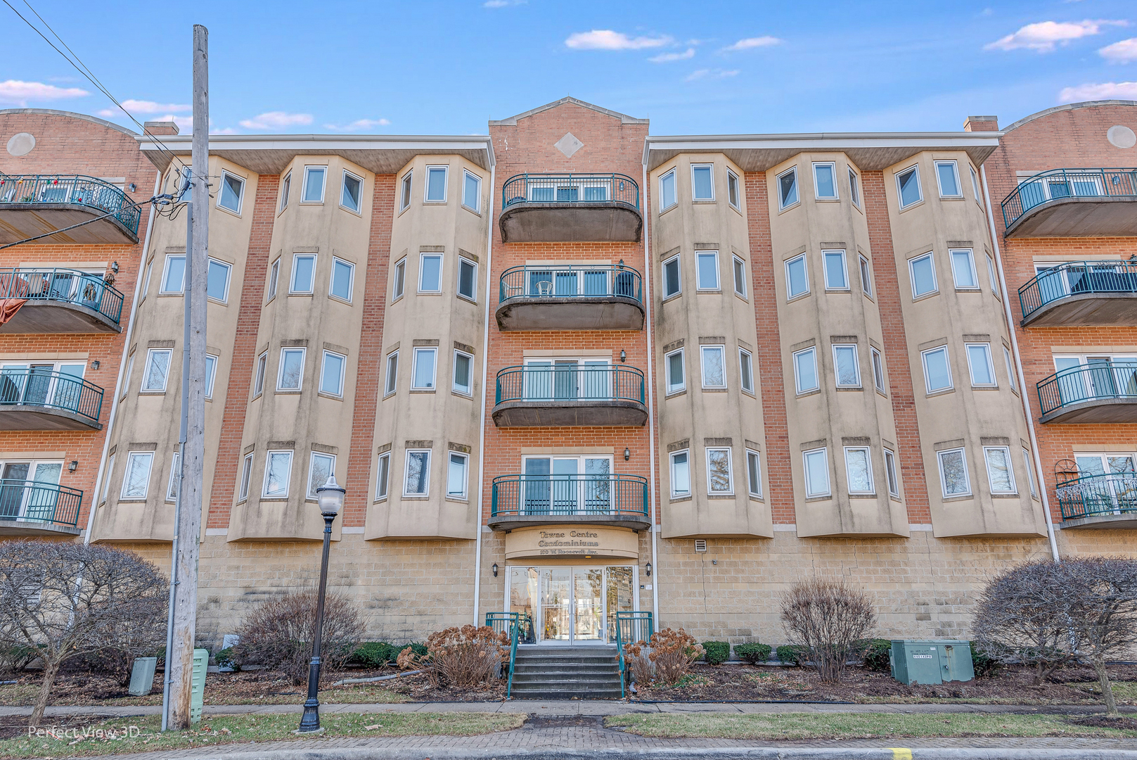 a front view of a residential apartment building with a yard and parking space