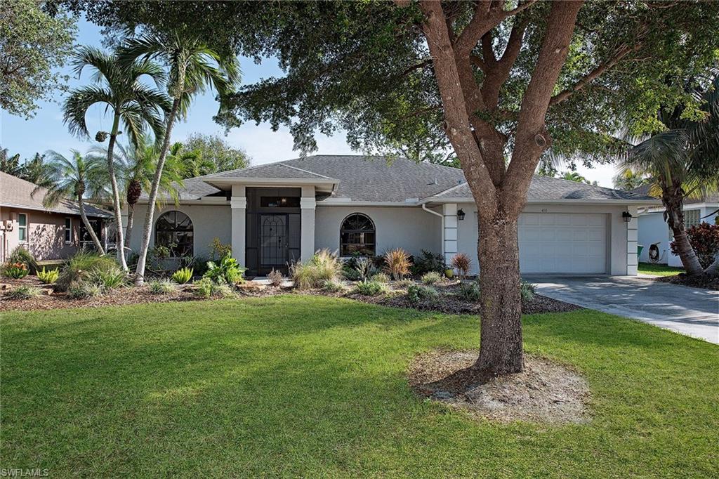 a front view of a house with garden and trees