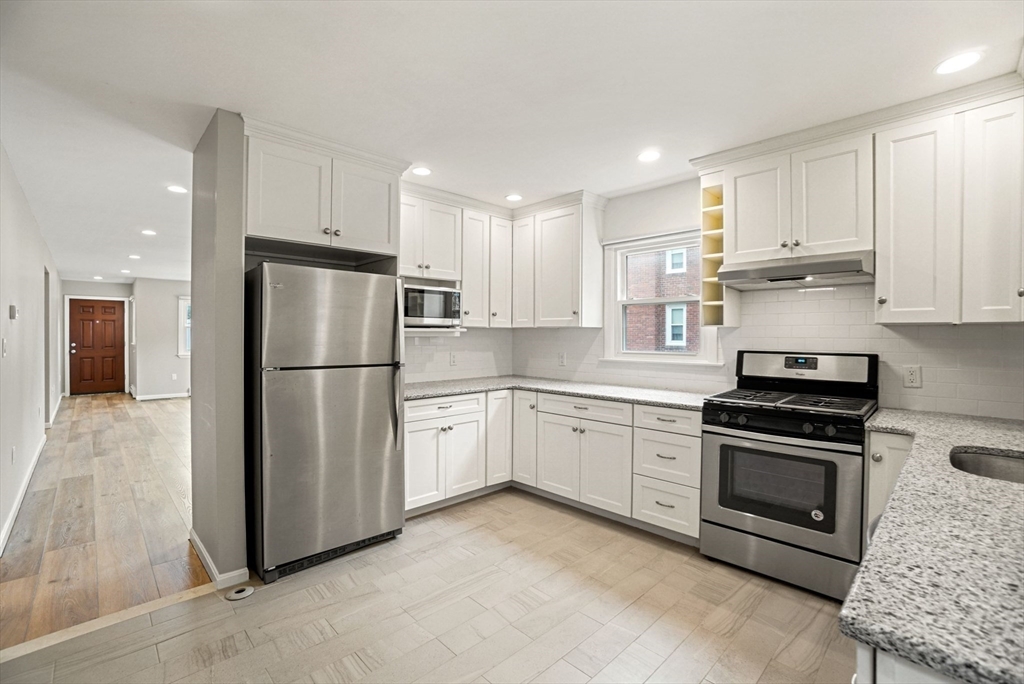 a kitchen with stainless steel appliances granite countertop a refrigerator sink and stove