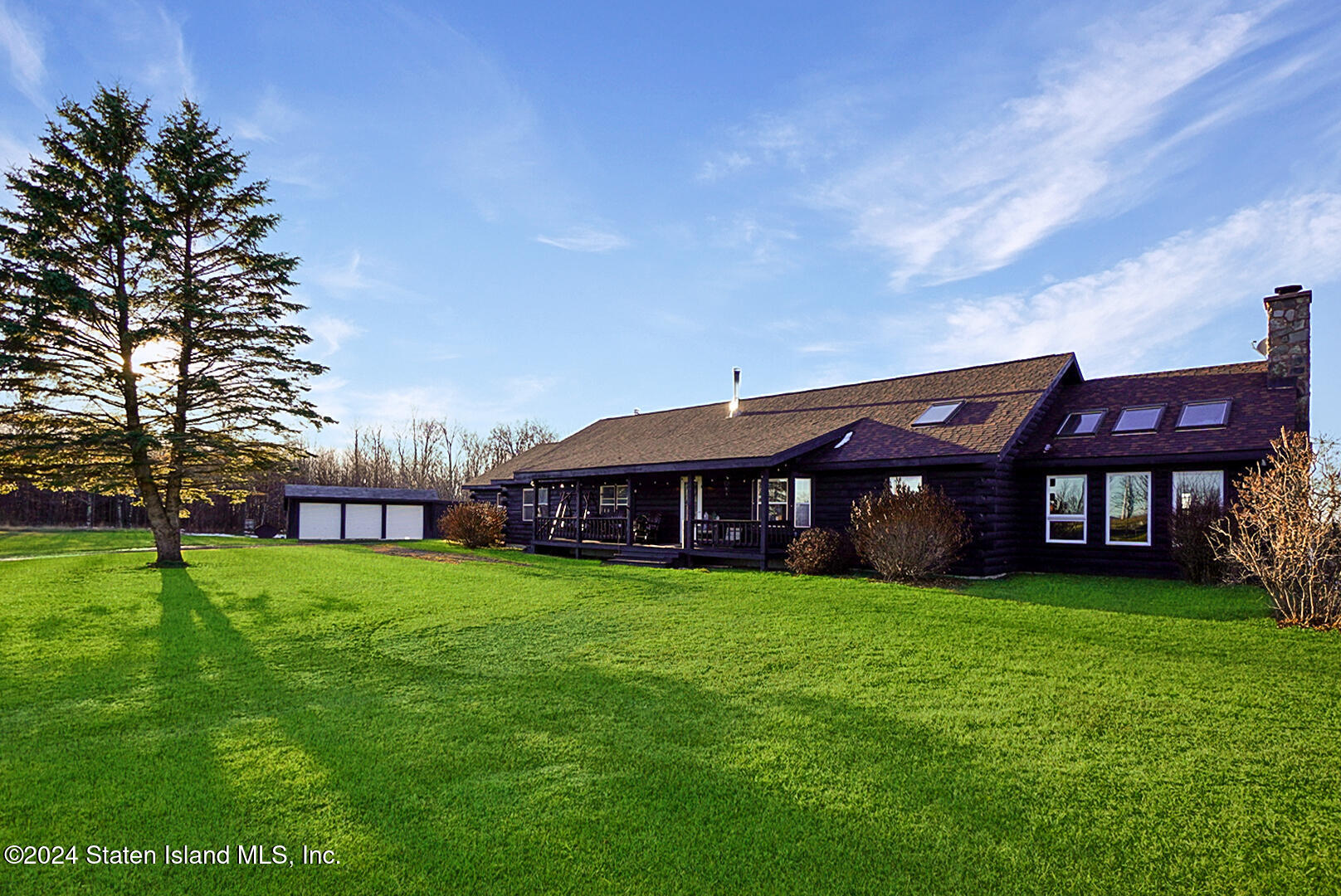 a view of a house with a big yard and large trees