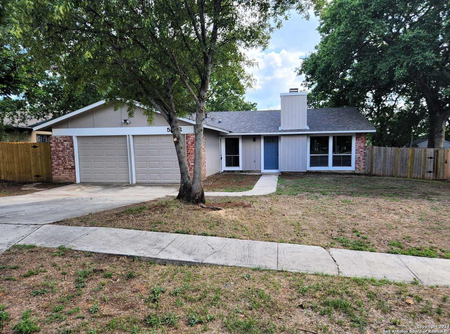 a view of a house with a yard and large tree