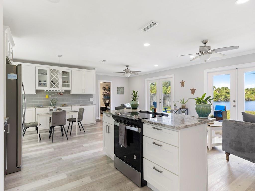 a kitchen with a dining table chairs stove and white cabinets