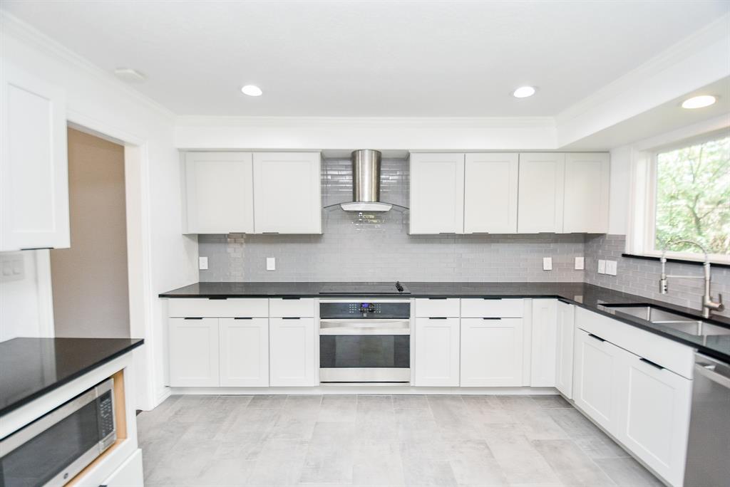 a kitchen with stainless steel appliances granite countertop a stove a sink and white cabinets