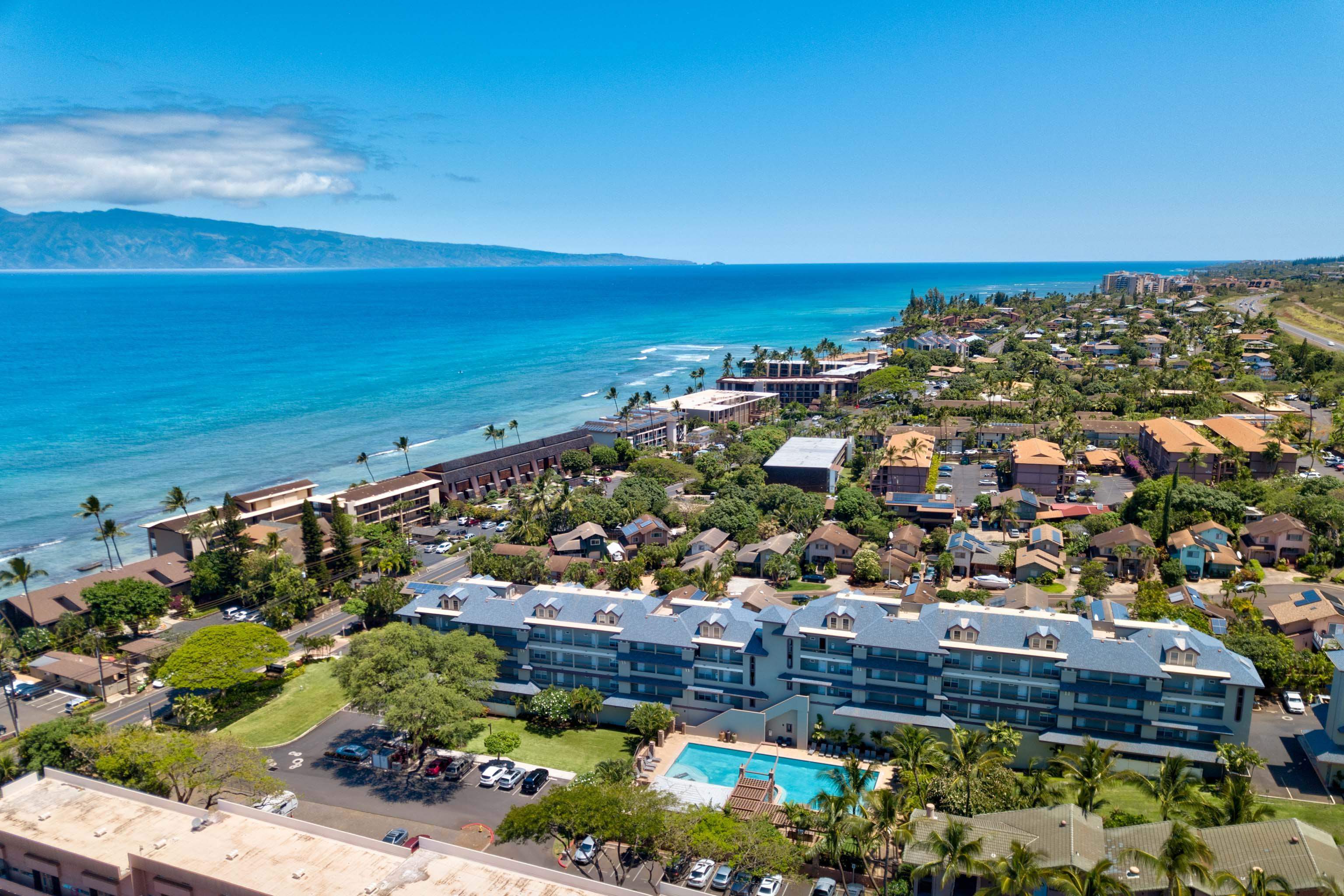 an aerial view of a city with lots of residential buildings and ocean view in back