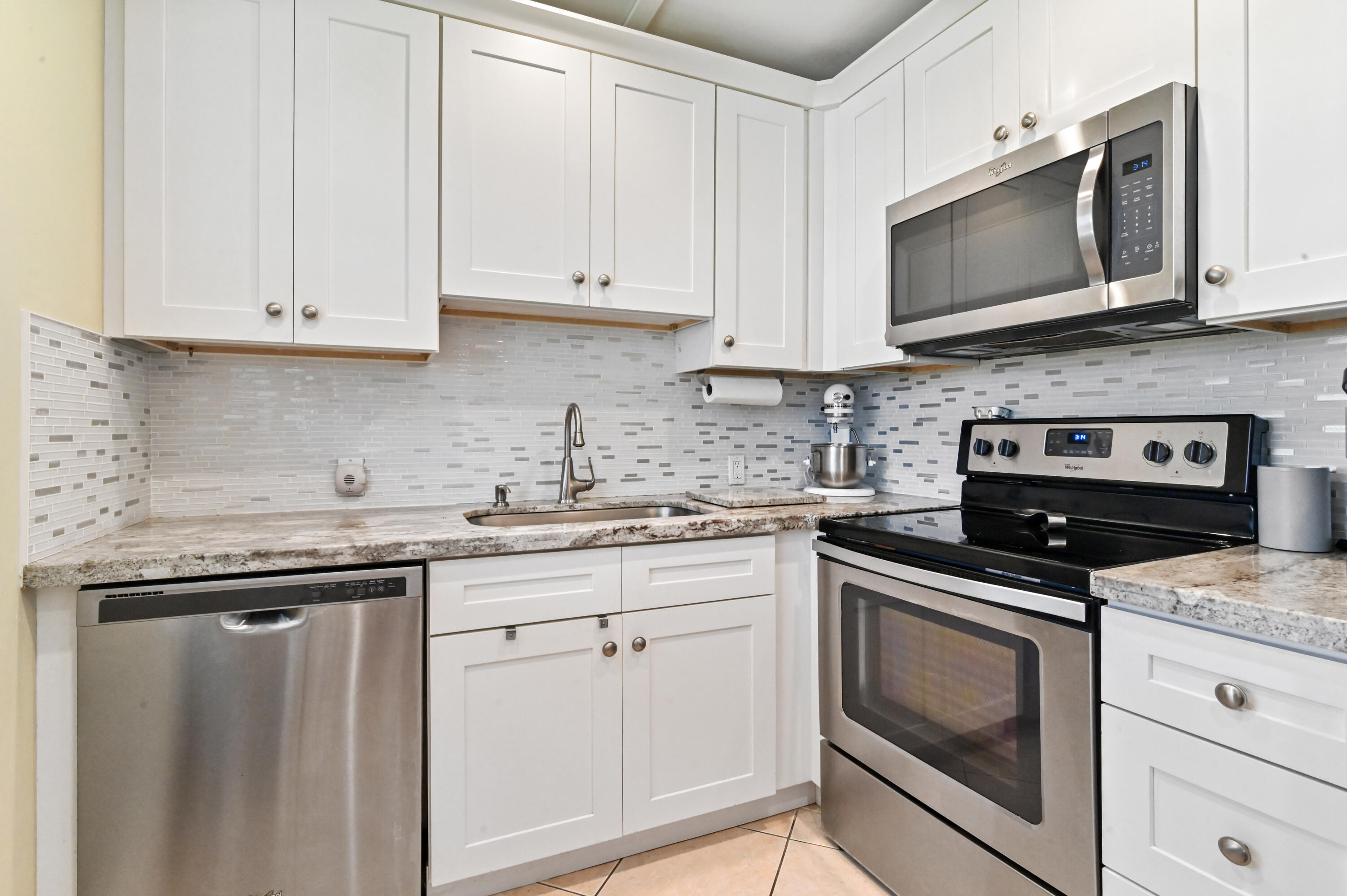 a kitchen with granite countertop white cabinets and stainless steel appliances