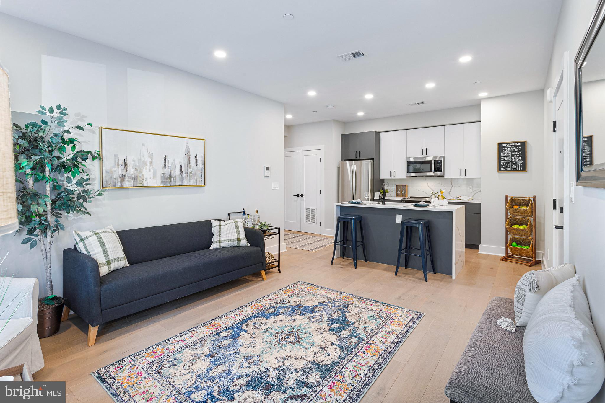 a living room with stainless steel appliances kitchen island granite countertop furniture a rug and a kitchen view