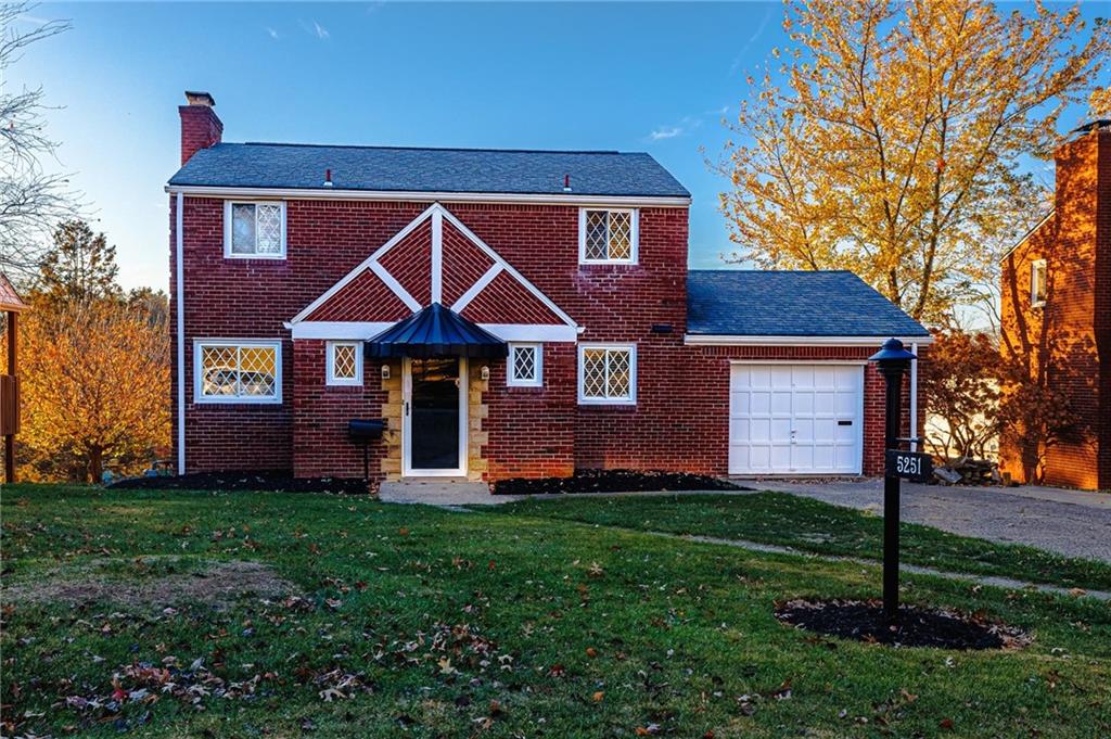 a front view of a house with a yard and trees