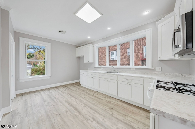 a large white kitchen with stainless steel appliances granite countertop a stove and a sink