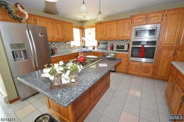 a kitchen with stainless steel appliances granite countertop a refrigerator a stove and a sink