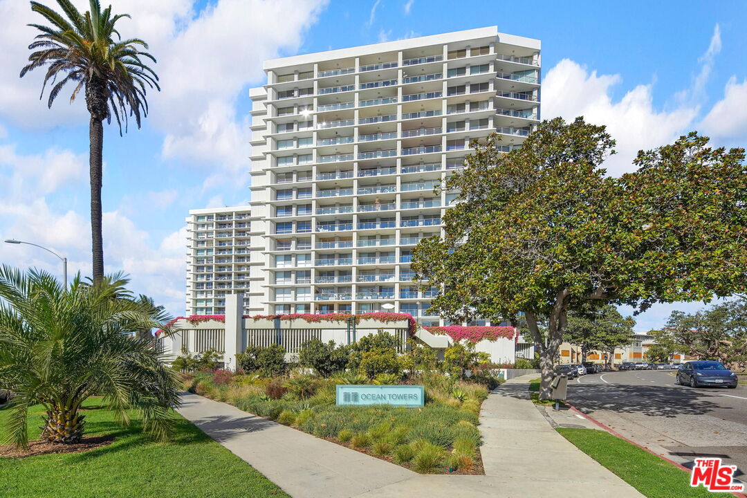 a front view of multi story residential apartment building with yard and sign board