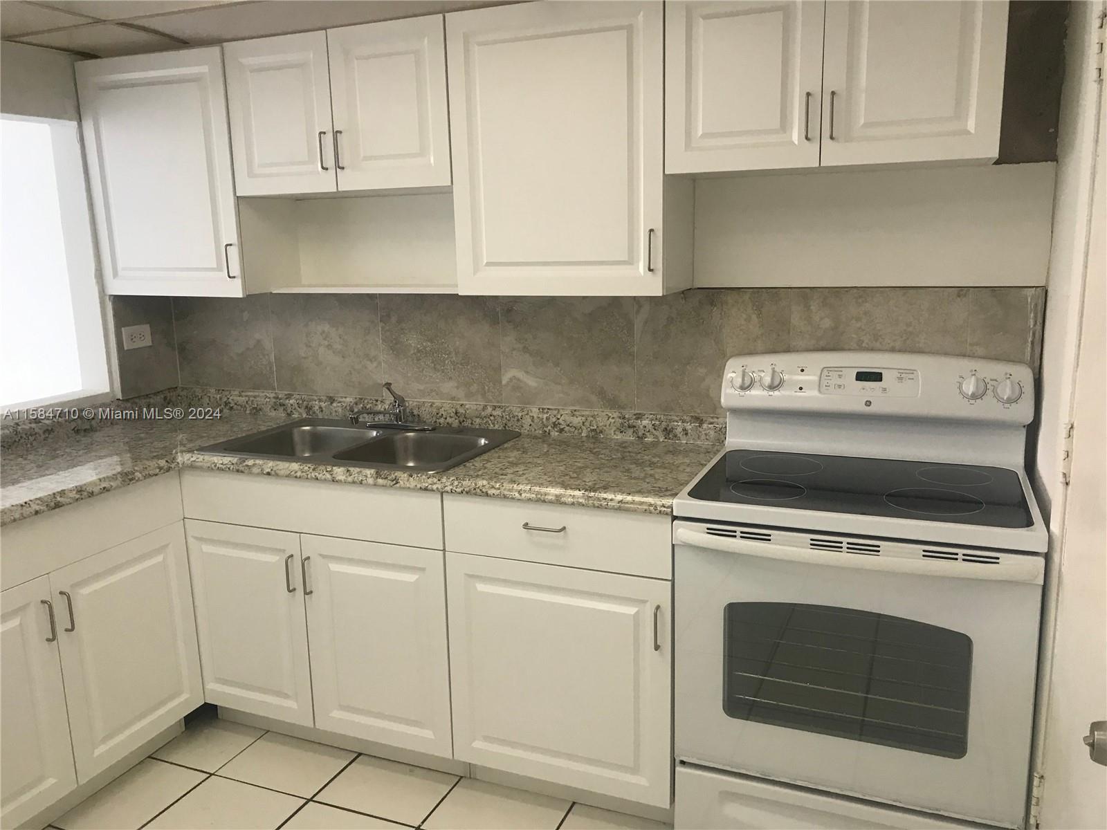 a kitchen with granite countertop white cabinets and white stove