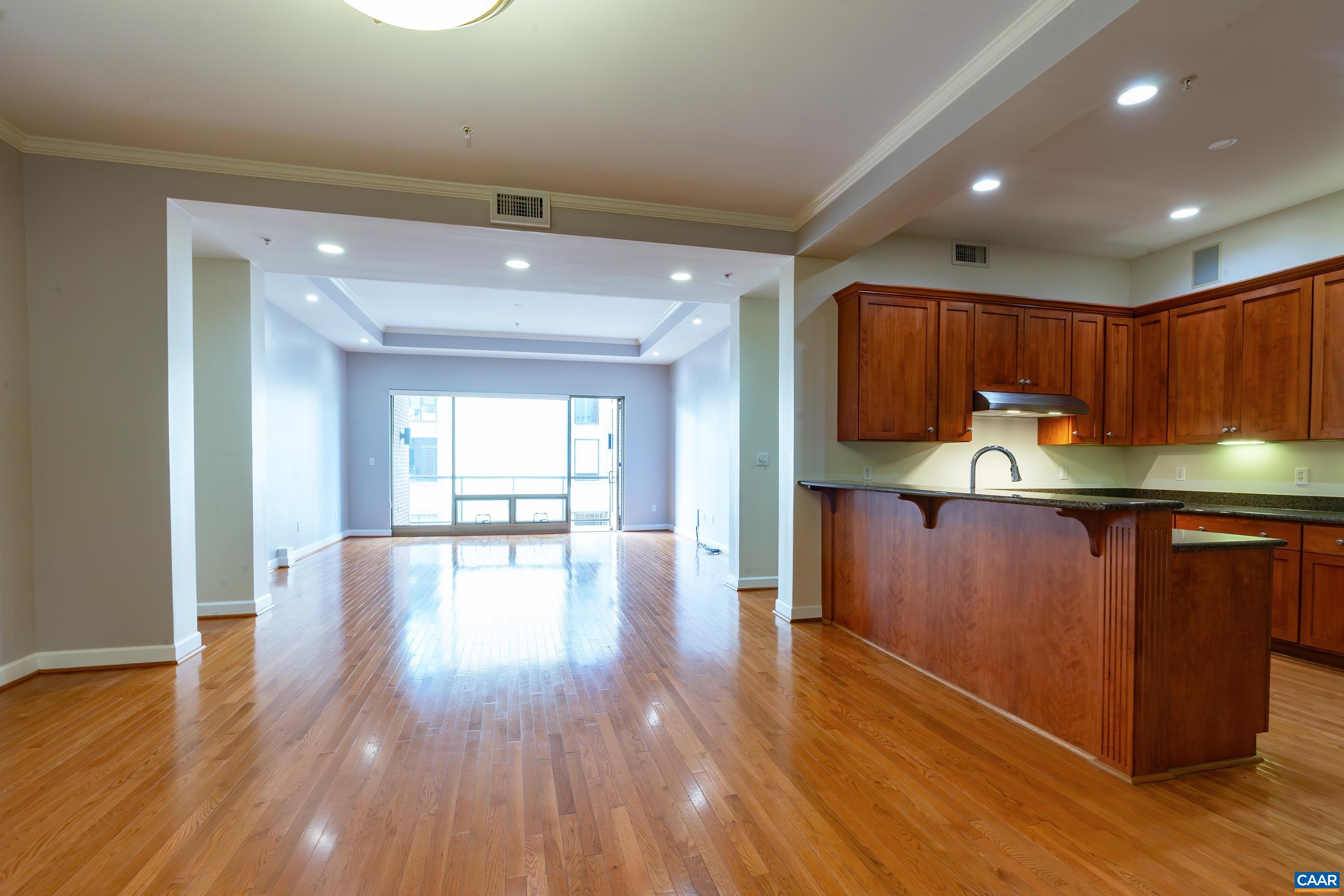 a kitchen with granite countertop wooden floors wooden cabinets a center island and stainless steel appliances