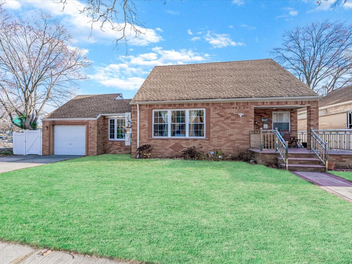 View of front of home with a porch, a garage, and a front yard