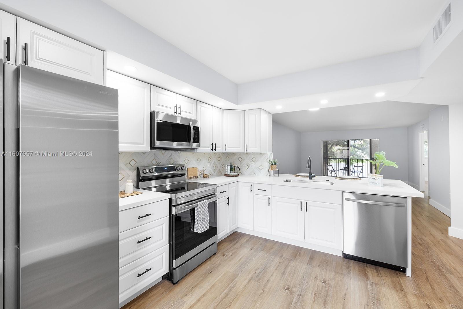 a kitchen with stainless steel appliances kitchen island granite countertop a stove top oven a sink dishwasher and a refrigerator with wooden floor