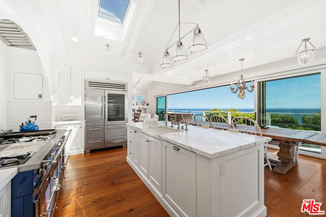 a large kitchen with kitchen island a large counter top space a sink stainless steel appliances and cabinets