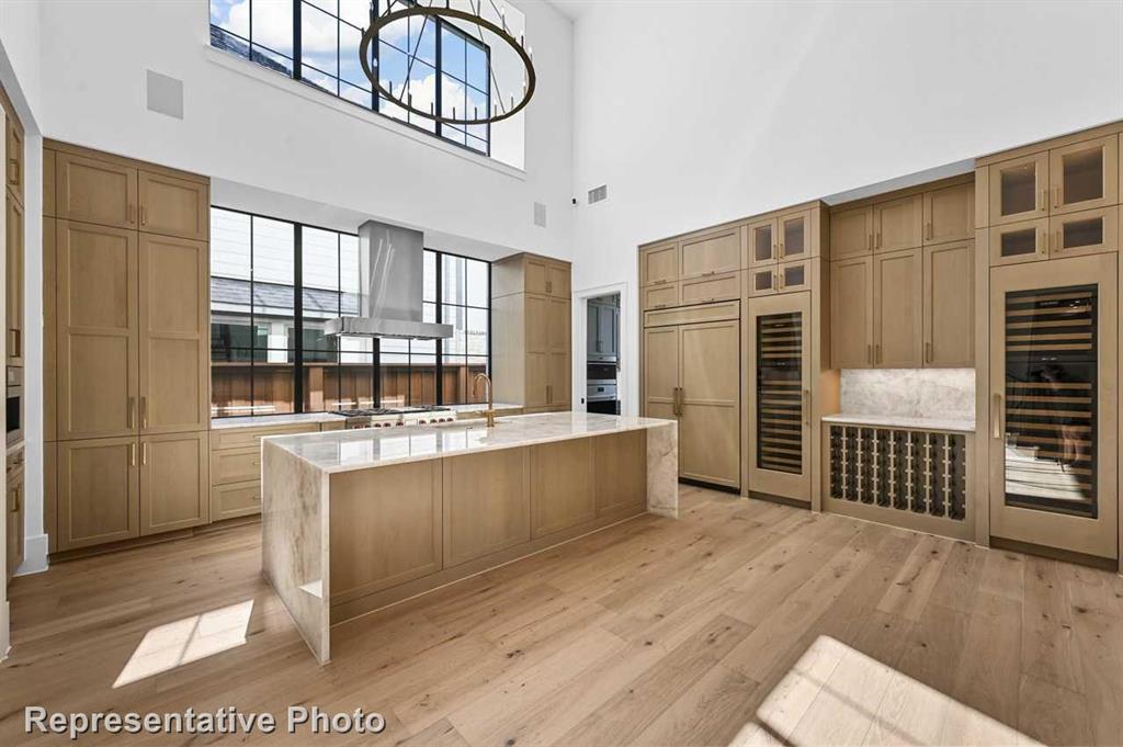 a large white kitchen with wooden floor and a large window