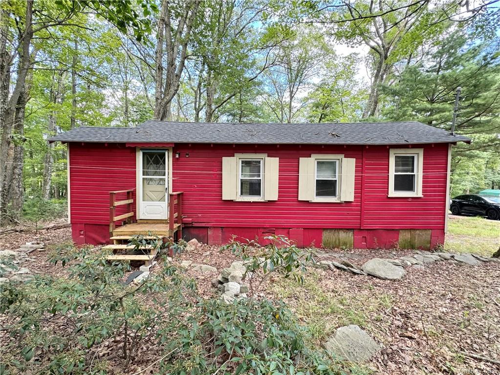 a view of a small house in front of a yard